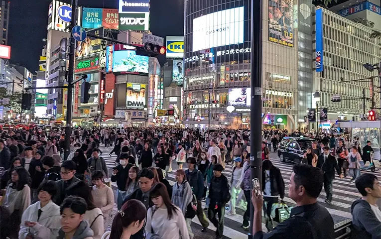 Many people crossing the bustling Shibuya Scramble Crossing at night