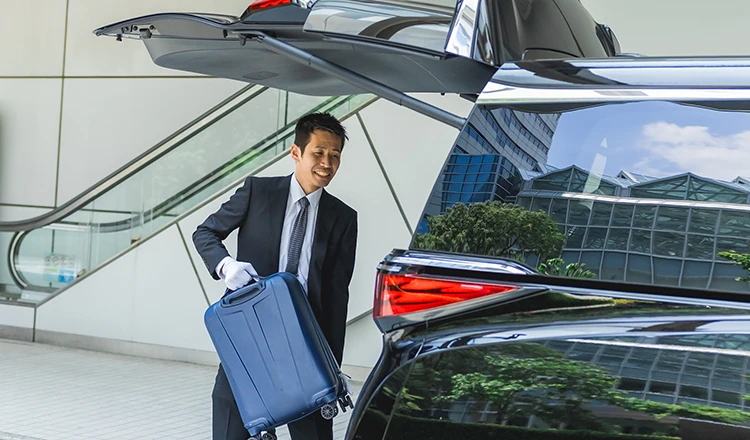 Chauffeur is loading customer's luggage into the car.